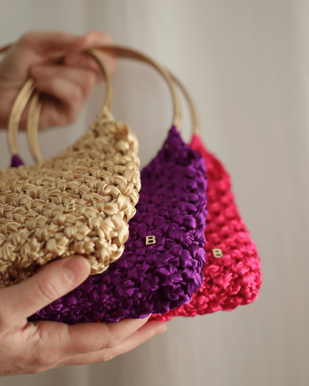 Roma Bag de color dorado, morado y fucsia. Vista en detalle de la B de Bimbú en la esquina inferior derecha.