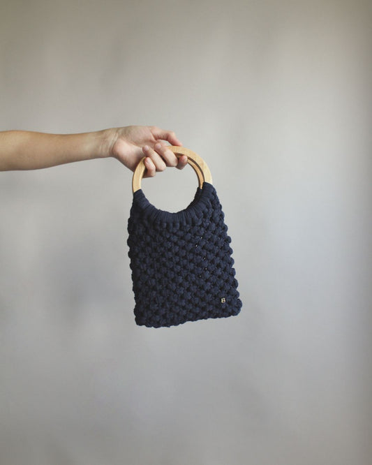 Gala Bag en color azul marino, sujetado por el asa de madera.