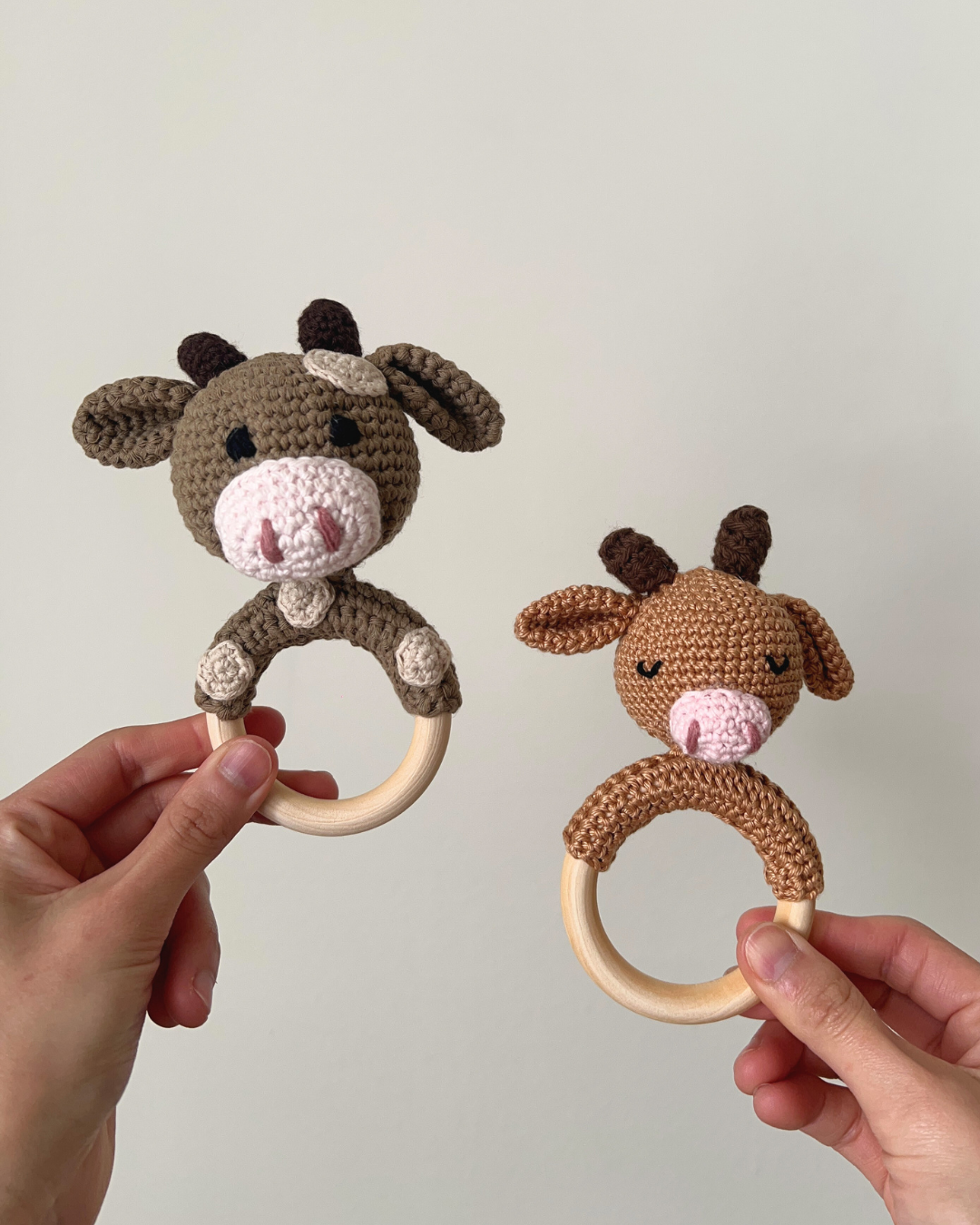 Dos sonajeros Mel en forma de vaquita, personalizados y tejidos a mano en tonos camel y marrón.