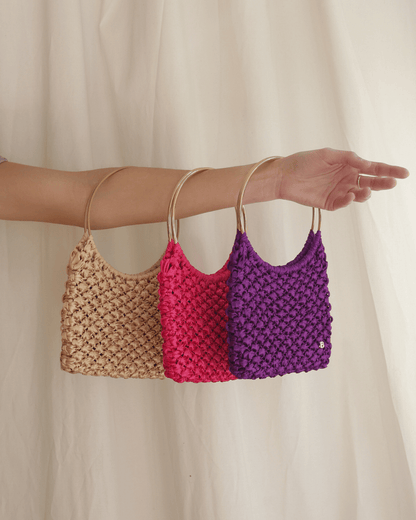 Roma Bag de raso dorado, fucsia y morado. Colocados en un brazo por el asa dorada.