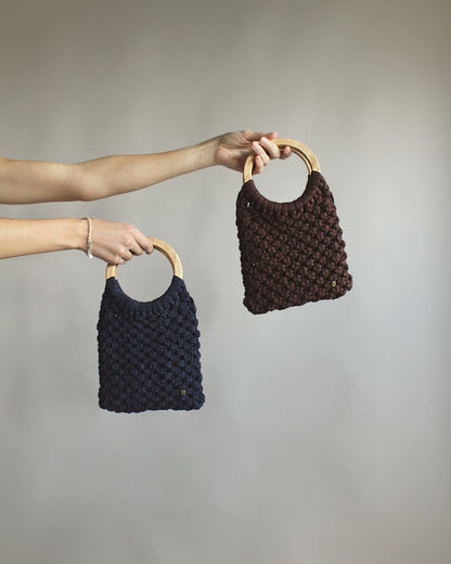 Gala Bag azul marino y marrón, sujetados por las asas de madera.