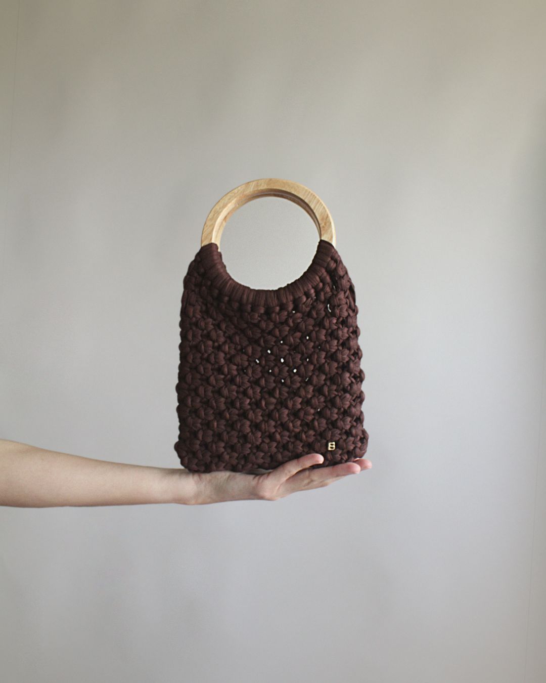 Gala Bag en color marrón, sujetado por la base. Vista frontal.