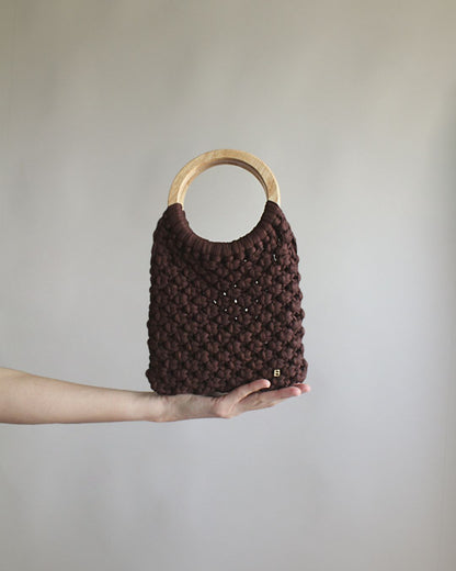 Gala Bag en color marrón, sujetado por la base. Vista frontal.