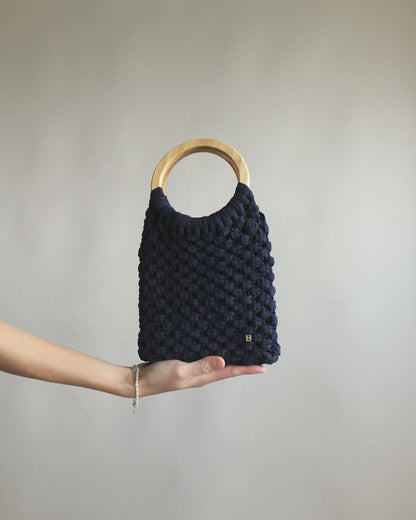 Gala Bag en color azul marino, sujetado por la base. Vista frontal.